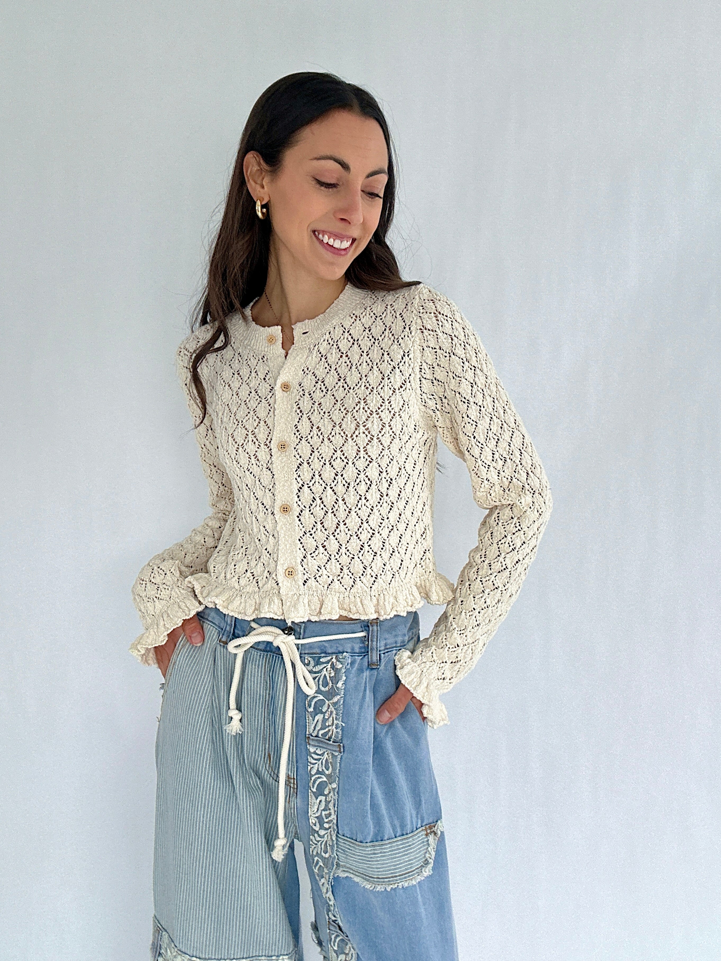 Woman wearing a cream lace cardigan with denim patchwork pants