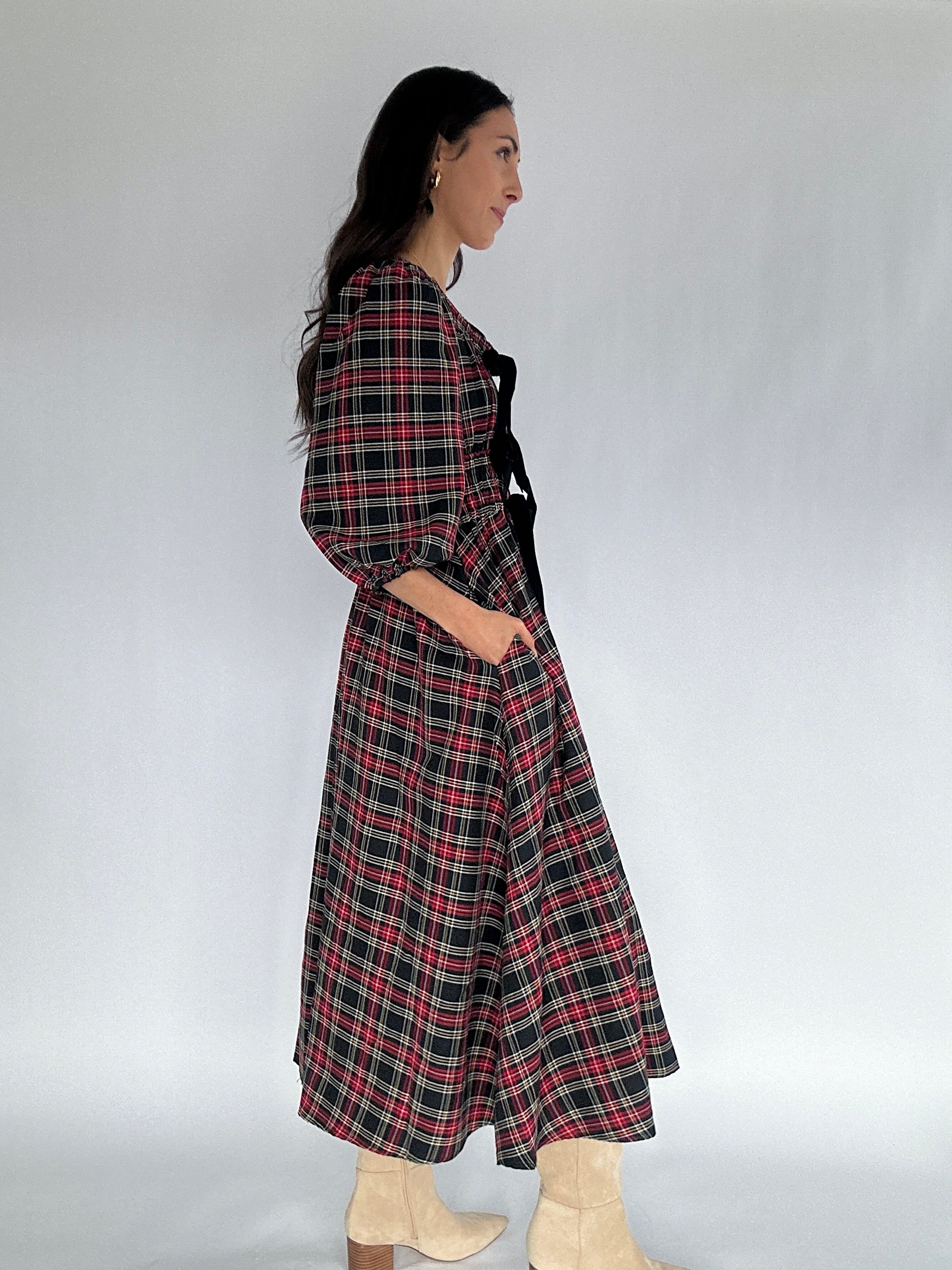 Woman wearing a plaid dress against a white background showing side and pockets