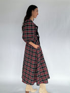 Woman wearing a plaid dress against a white background showing side and pockets