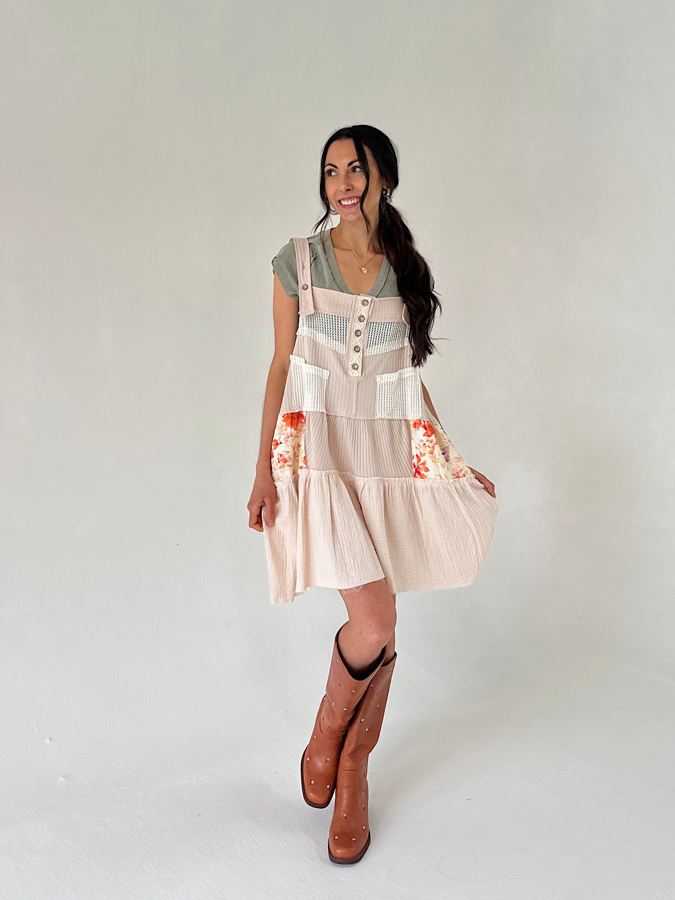 Woman wearing a patterned dress with floral designs on a plain background