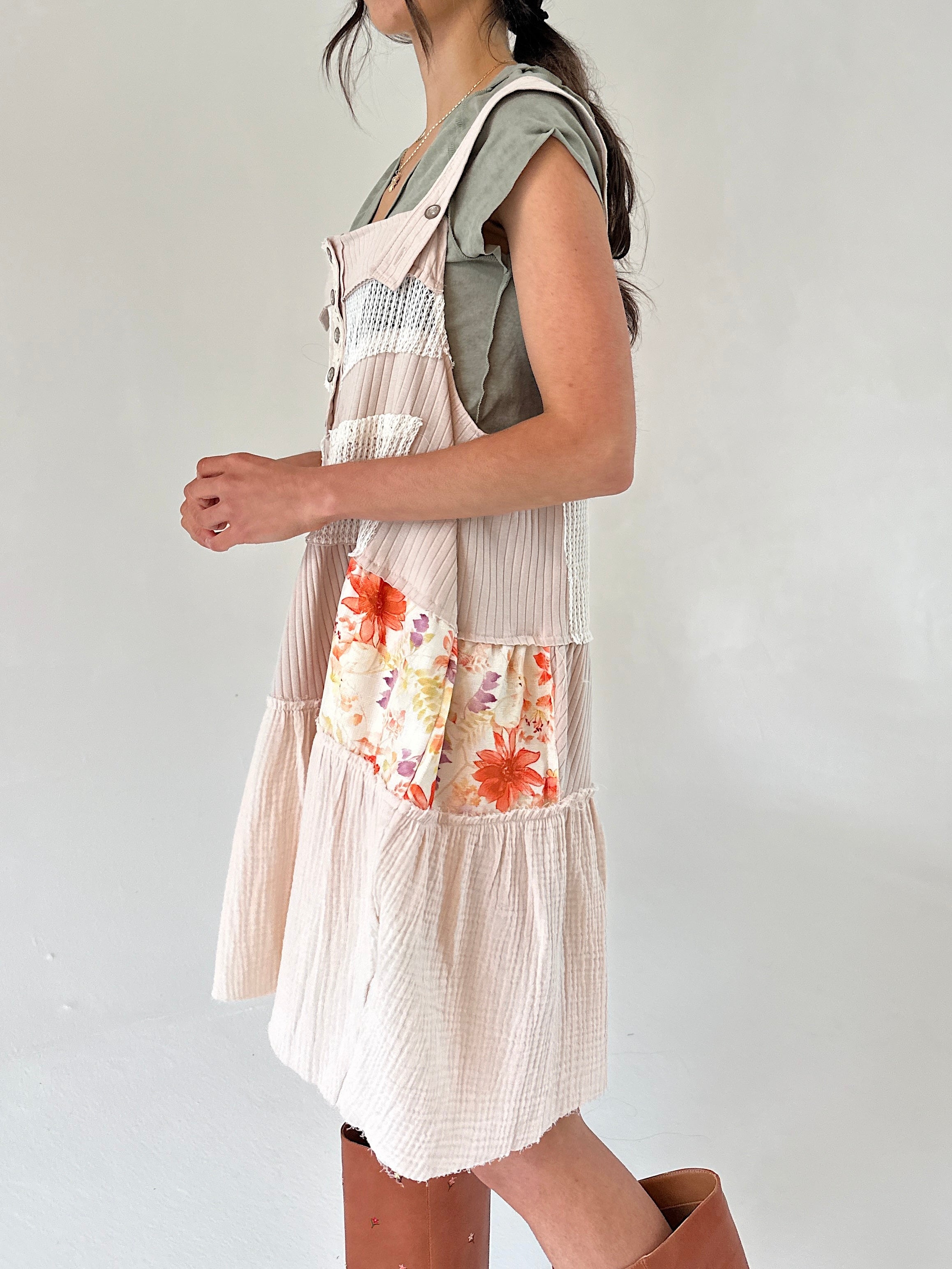 Person wearing a floral overall dress  with a plain background