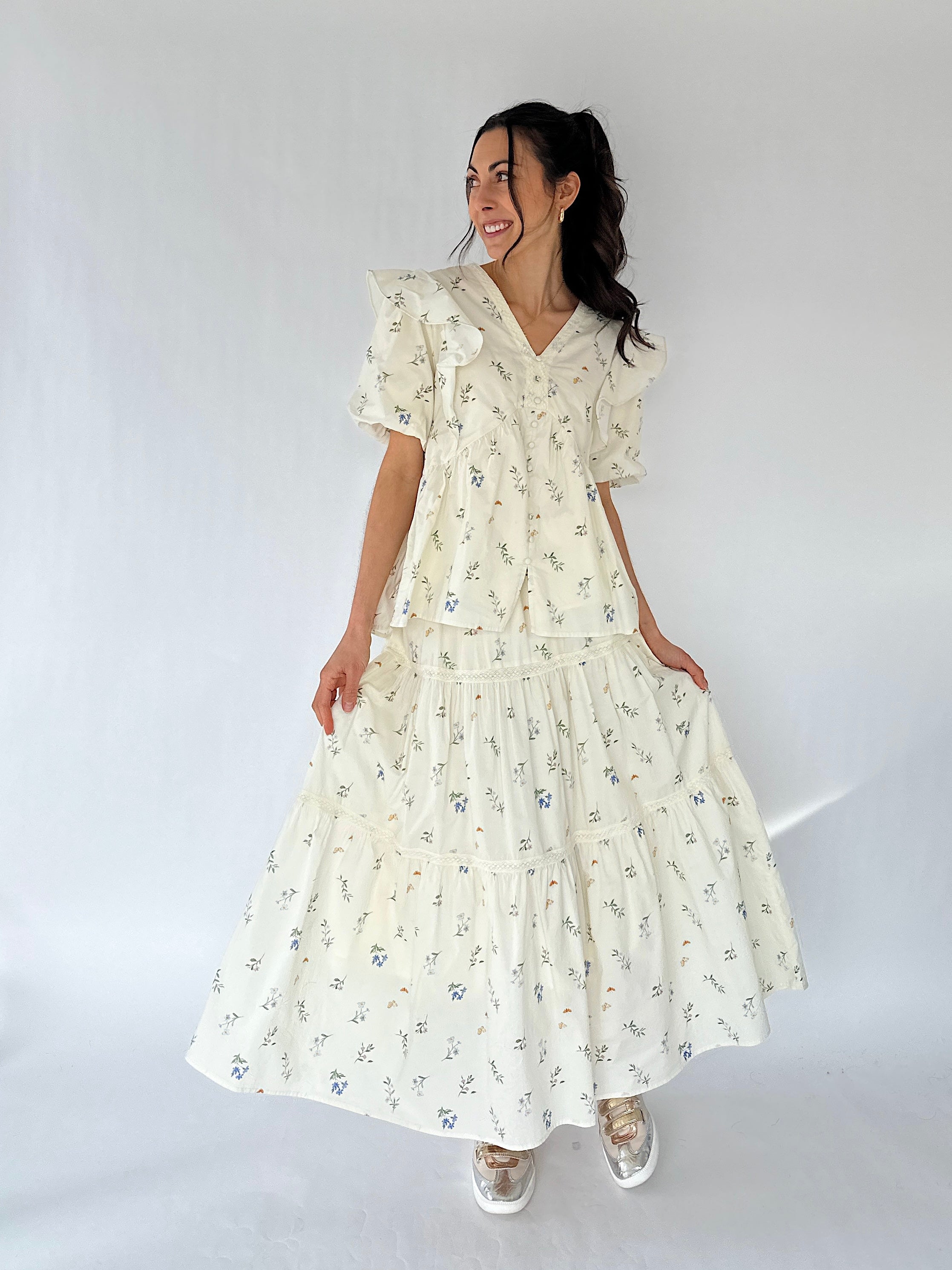 Woman wearing a floral maxi skirt and matching top against a white background
