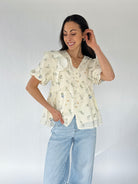 Woman wearing a floral blouse and light blue jeans against a white background