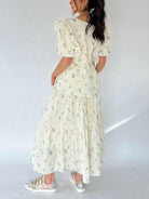 Woman wearing a floral maxi skirt and matching top from back on a white background