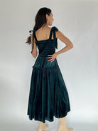 woman wearing teal velvet midi dress from back