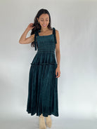 Woman wearing a dark green velvet dress against a white background