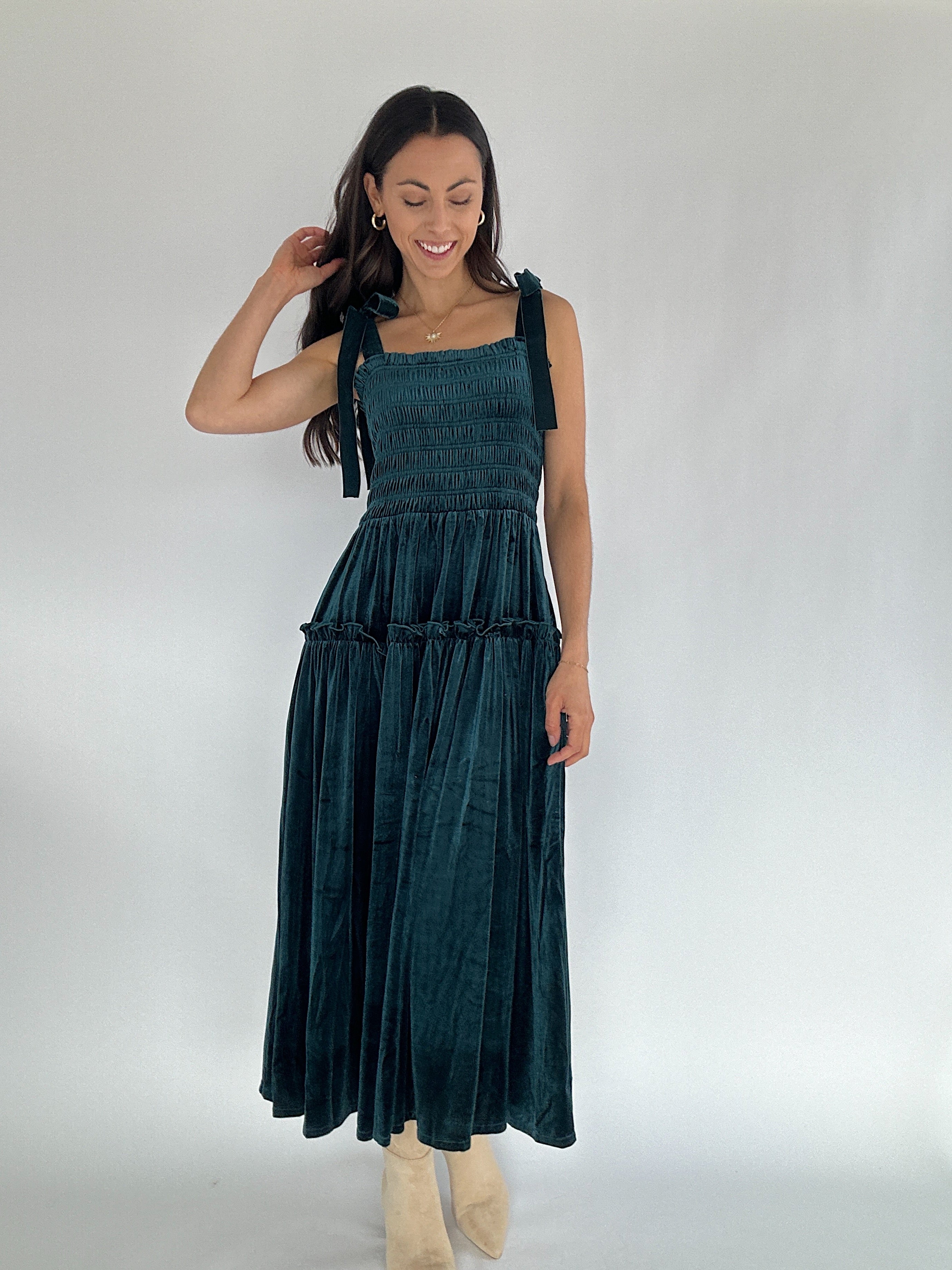 Woman wearing a dark green velvet dress against a white background