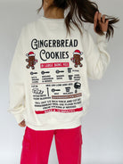 Person wearing a white sweatshirt with gingerbread cookies recipe embroidered graphic on the back.