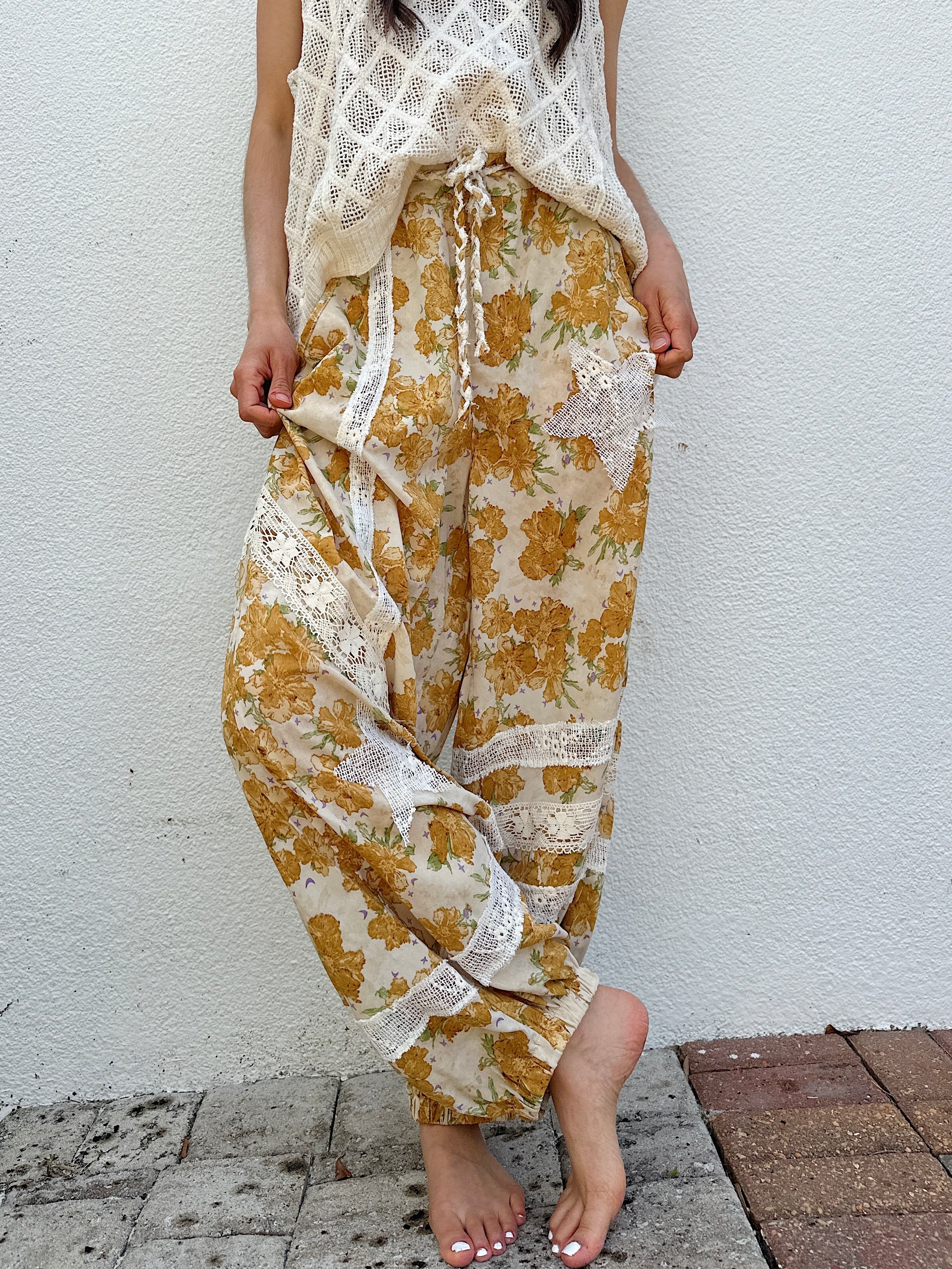 Person wearing a floral dress with lace details against a white wall.