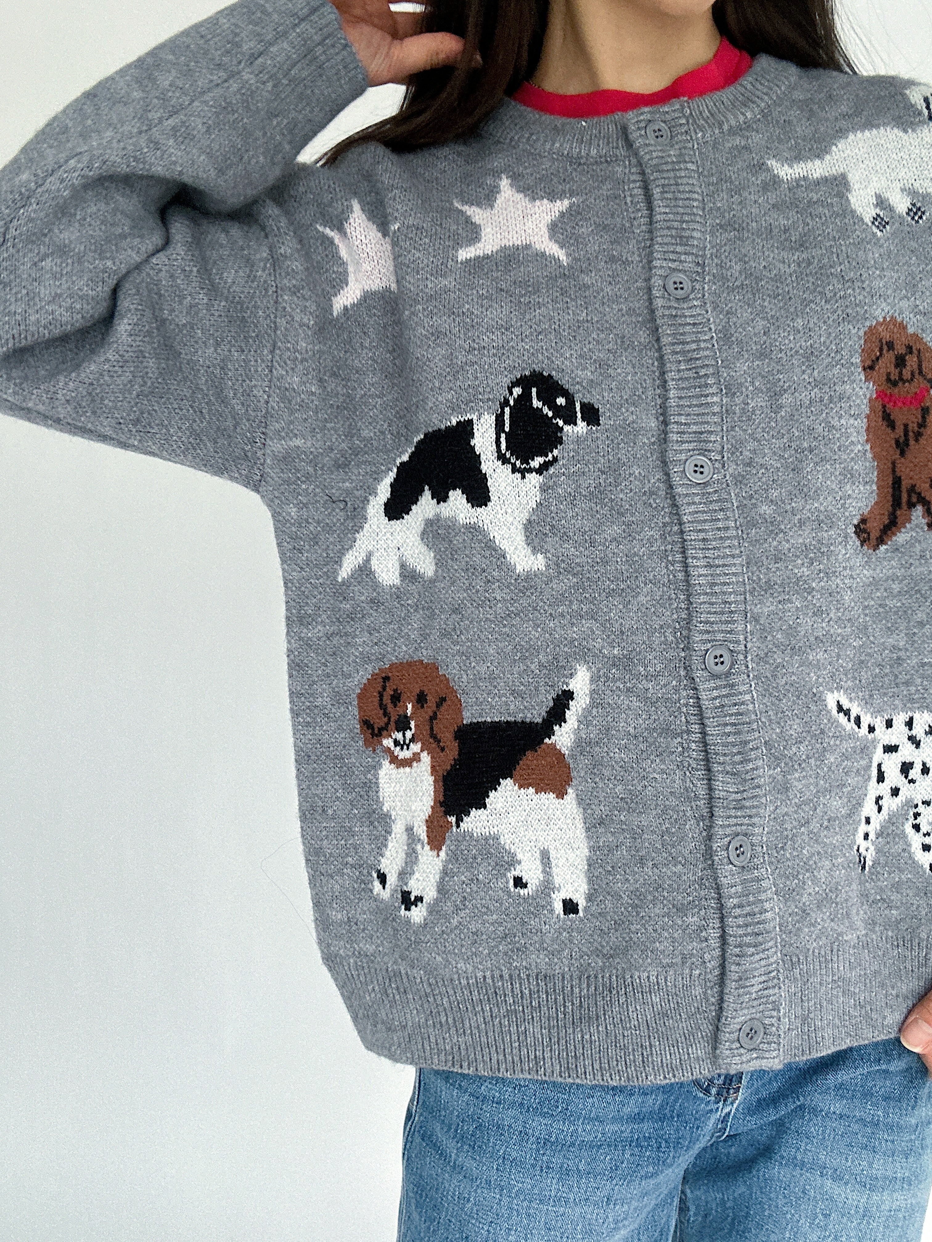 Gray cardigan with dog illustrations worn by a person on a light gray background