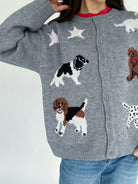 Gray cardigan with dog illustrations worn by a person on a light gray background