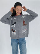 Woman wearing a gray cardigan sweater with dog illustrations buttoned with jeans on a white background