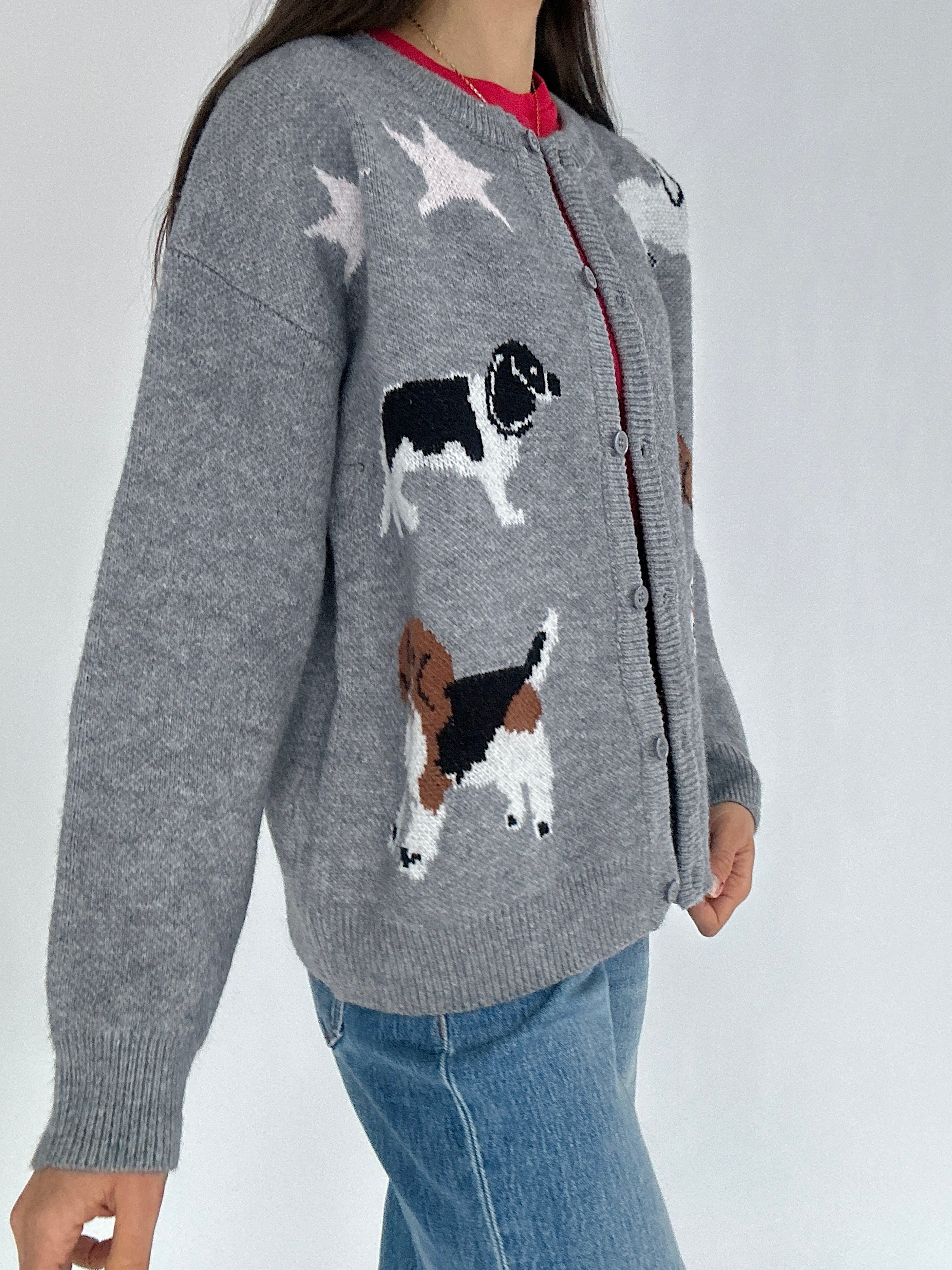 Person wearing a gray cardigan with dog illustrations on a white background