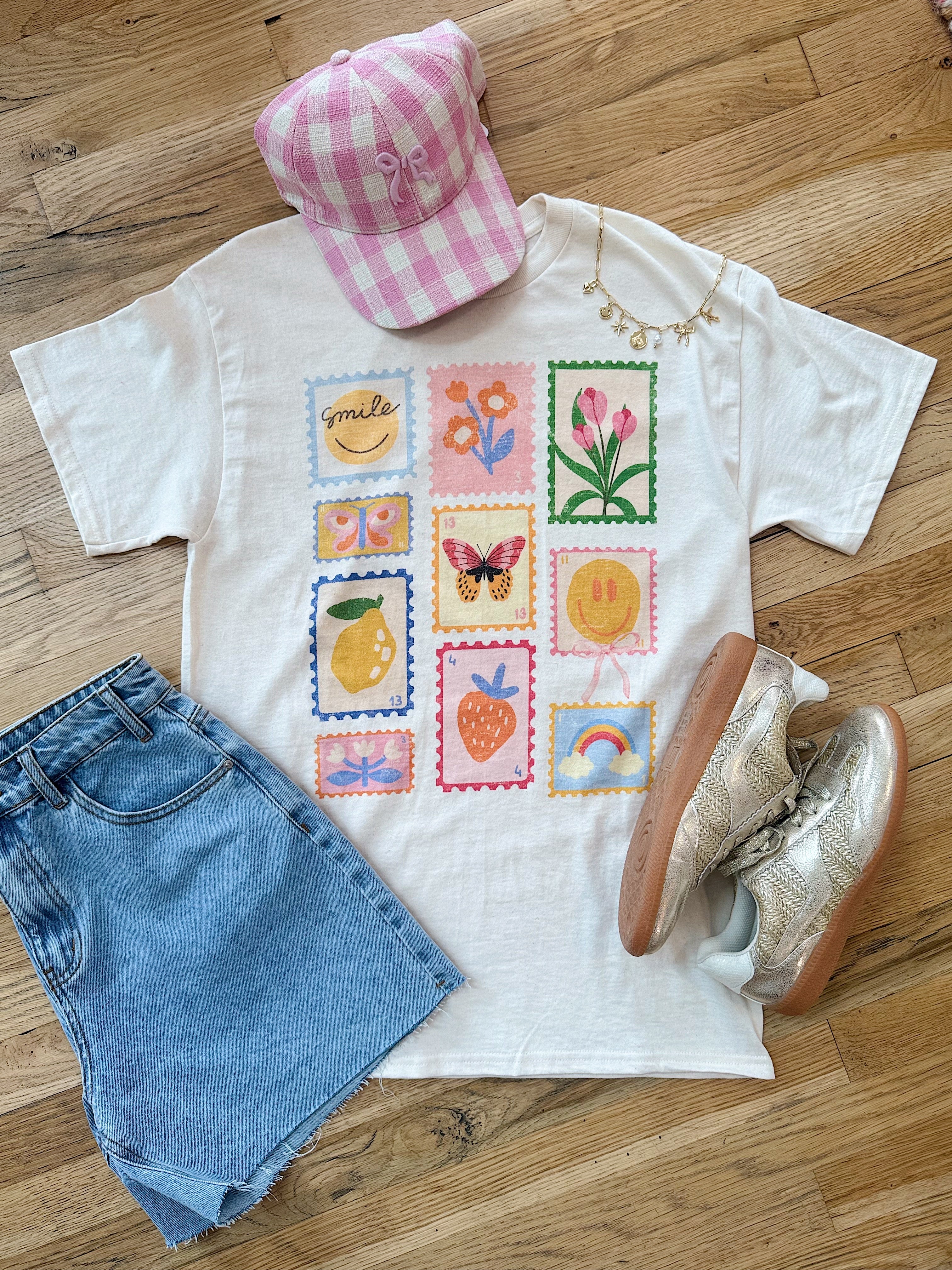 Good Vibes Stamp Oversized Tee with shorts, sneakers and a hat laid out on the ground