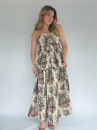 Woman wearing a floral tapestry strapless tiered dress against a plain background