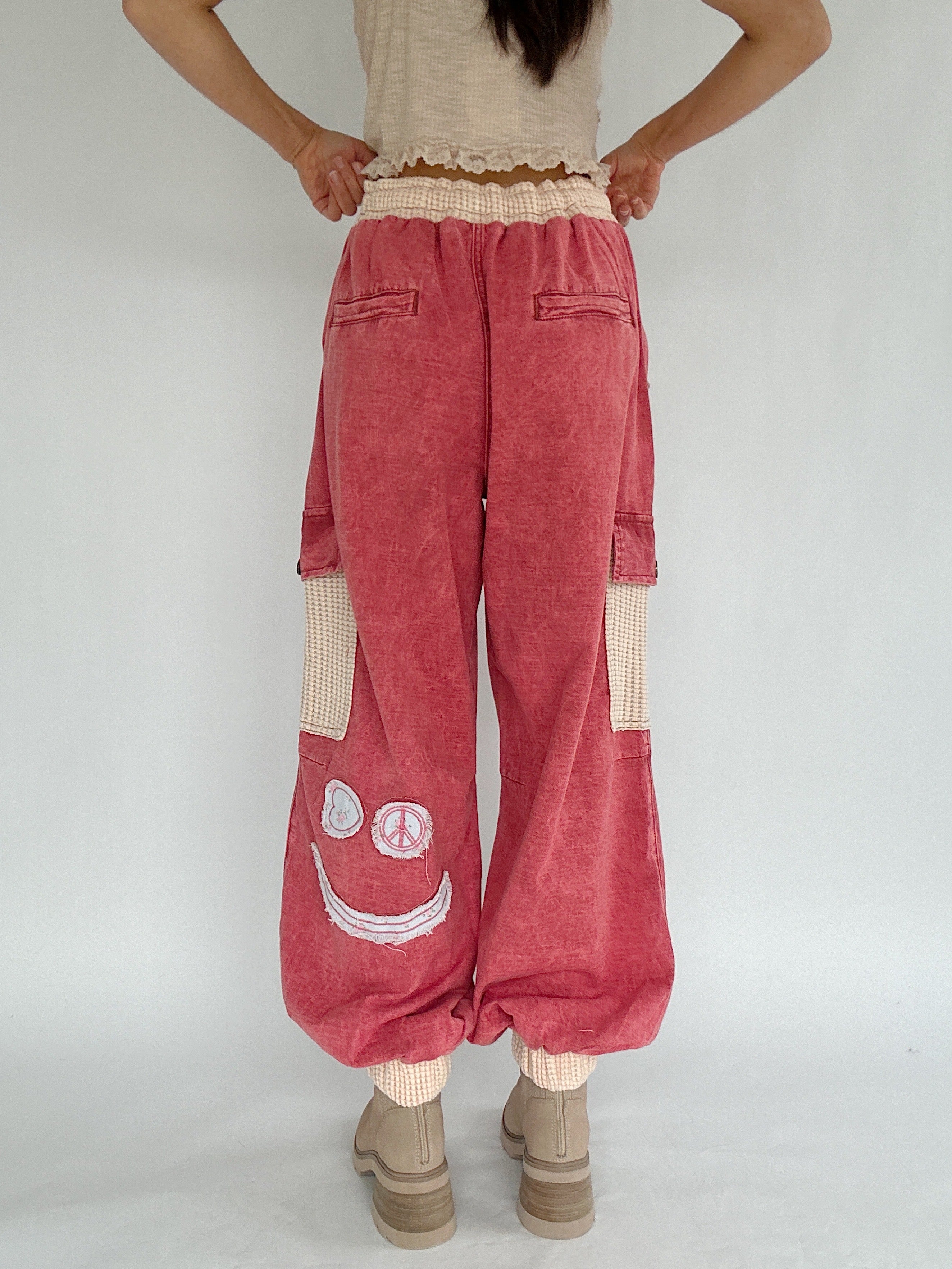 Person wearing red cargo pants with smiley face design on a plain background