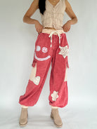 Person wearing red pants with smiley face and peace sign designs on a plain background