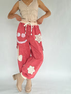 Person wearing red pants with white floral and peace symbol designs on a plain background