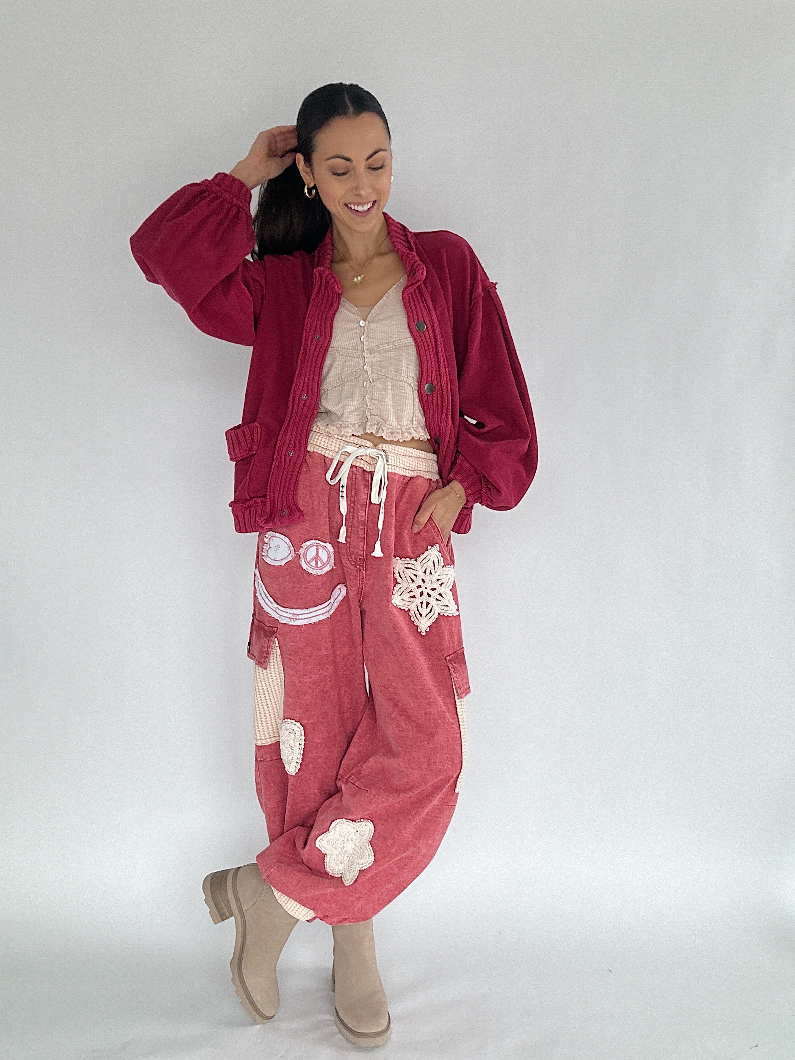 Woman wearing a red cardigan and red jogger pants with patchwork patterns on a white background