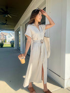 Woman wearing an oatmeal linen maxi dress carrying a coffee