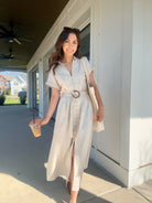 Woman wearing an oatmeal linen maxi dress with button front and waist belt, carrying a coffee.