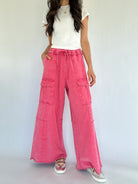 Person wearing pink wide-leg pants with cargo pockets and a white top on a plain background