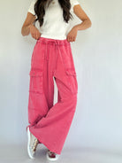 Person wearing pink cargo pants and a white top on a plain background