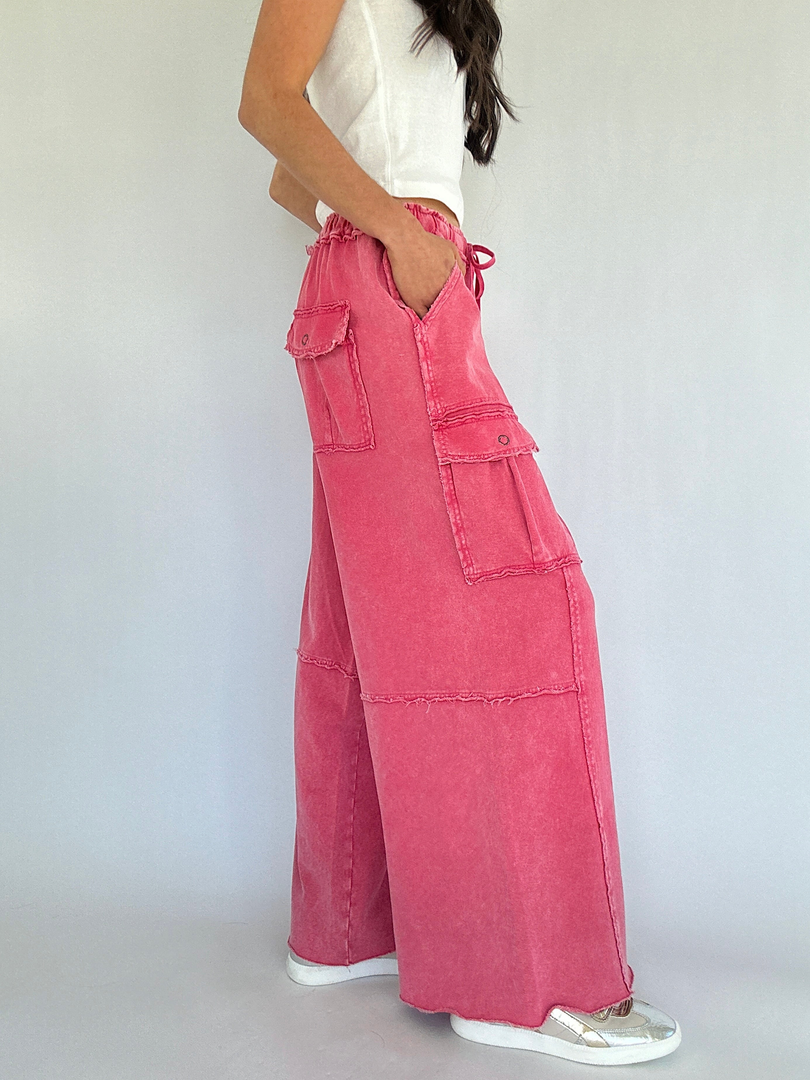 Person wearing pink wide-leg pants with a white top on a plain background showing the side