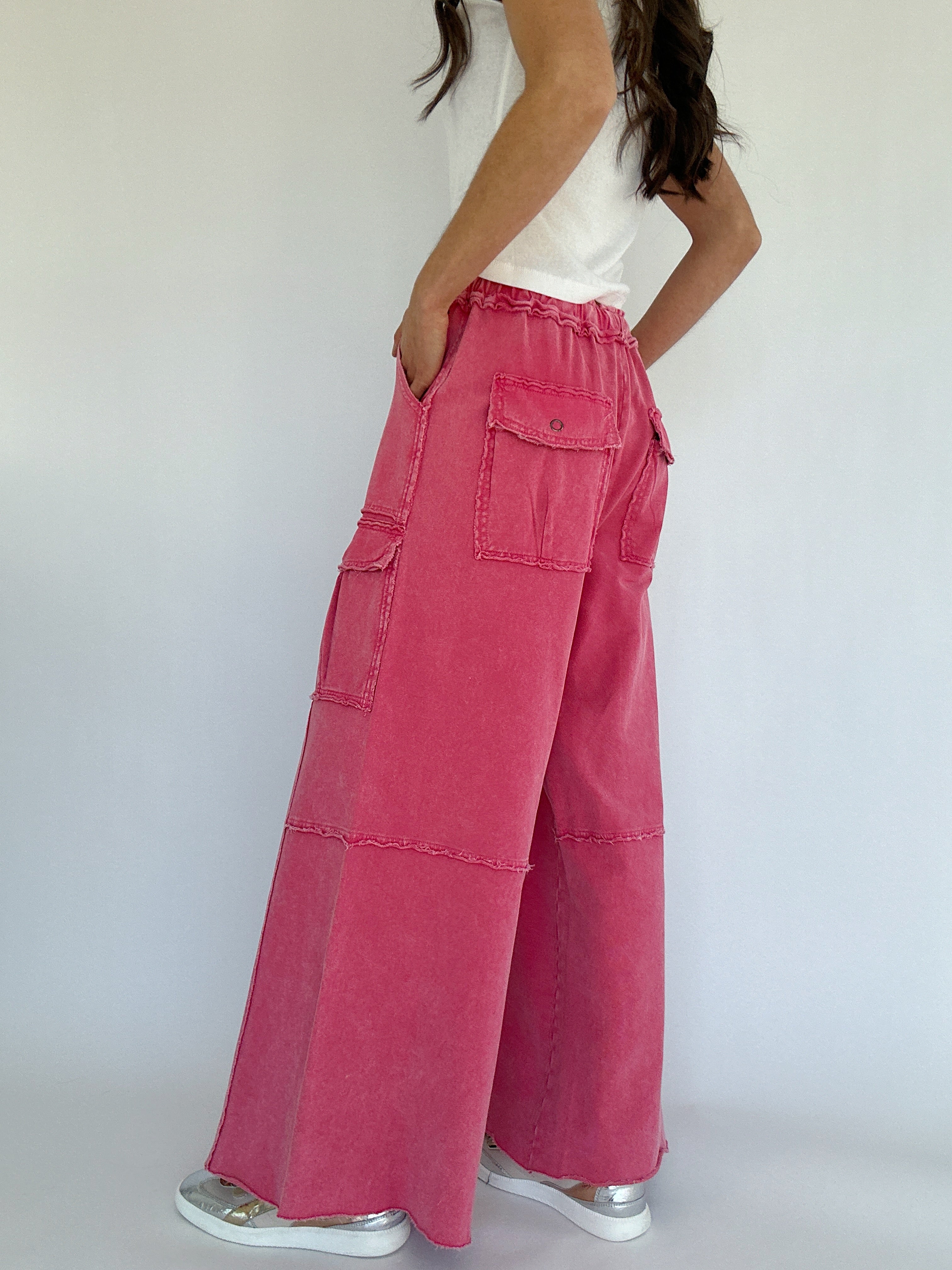 Person wearing pink wide-leg pants with a white top against a plain background