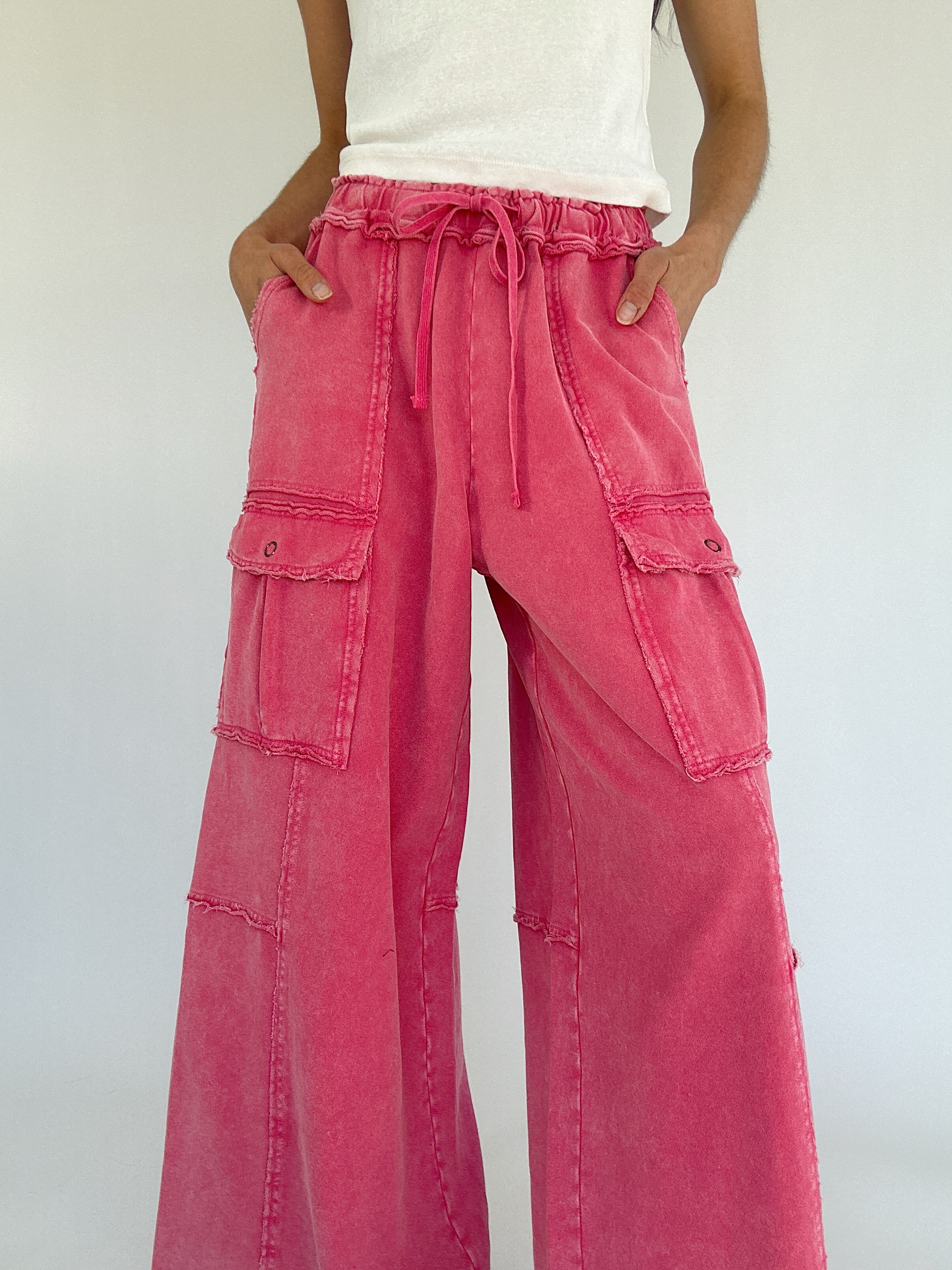 Person wearing bright pink cargo pants with a white background showing drawstring waist and side pockets