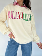 Person wearing a cream sweatshirt with 'YOLLY JOLLY' text, blue jeans, over a checkered button down on a white background