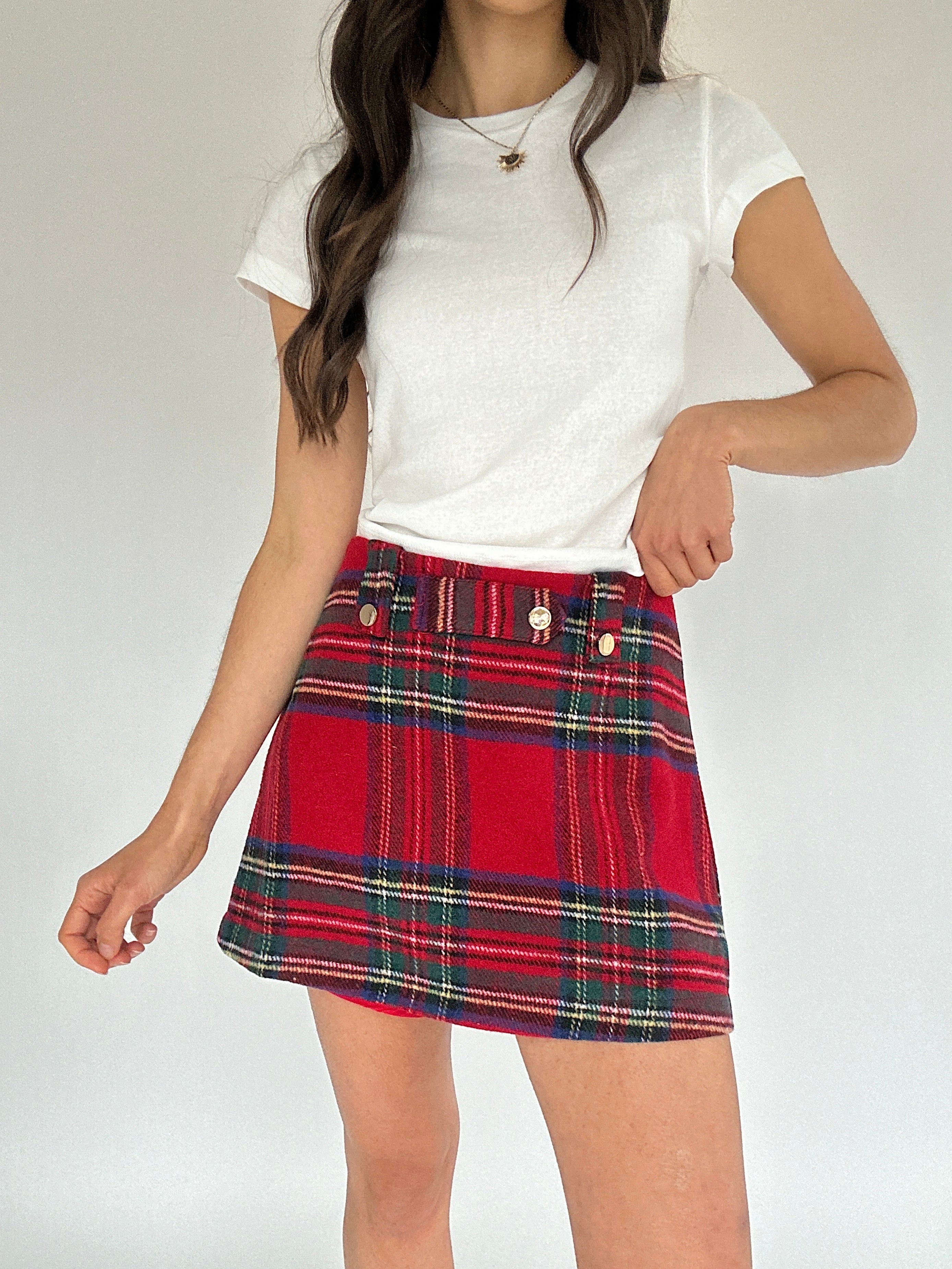 Person wearing a white t-shirt and red plaid mini skort on a plain background