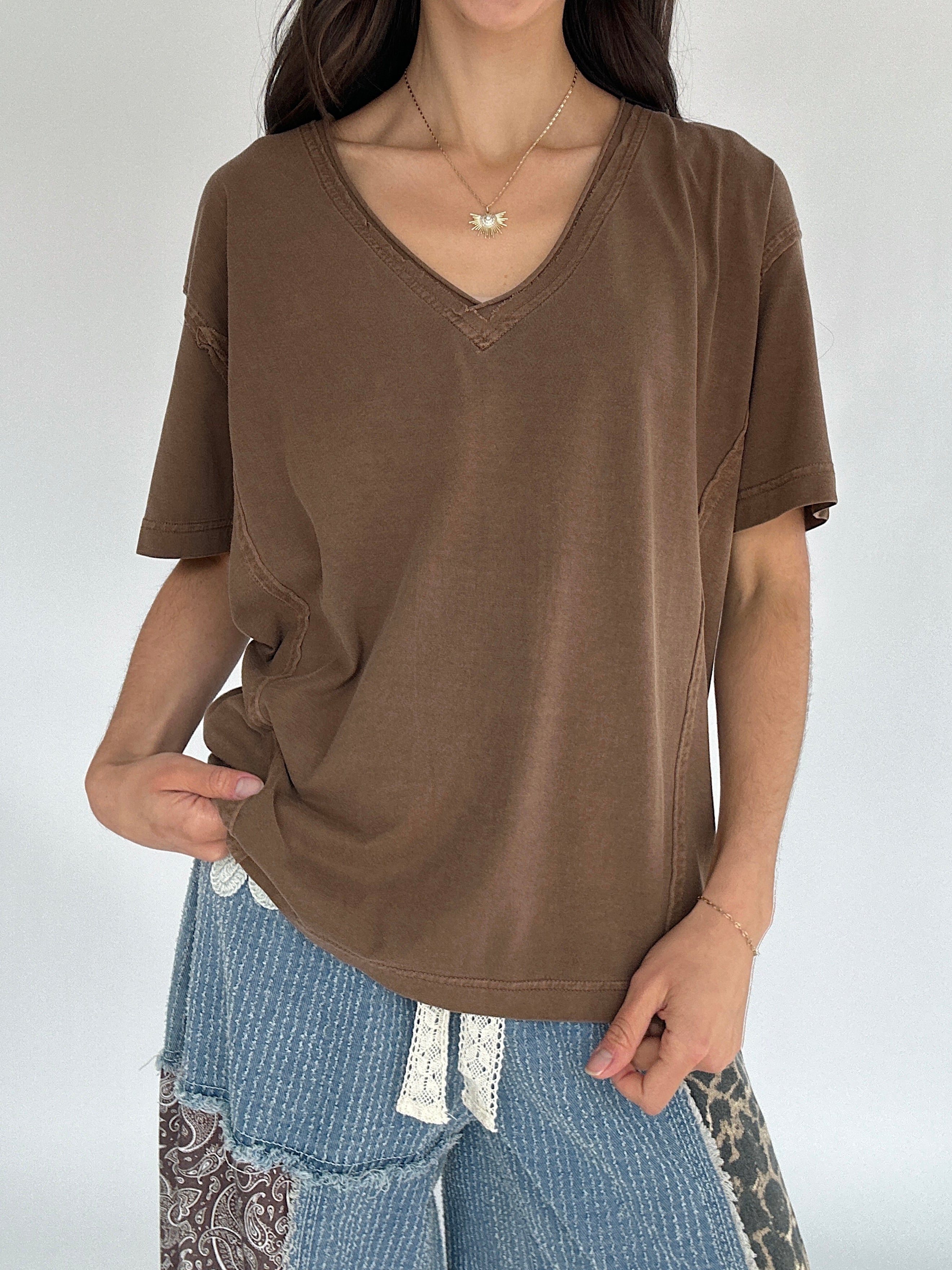 Person wearing a brown t-shirt and blue pants against a white background