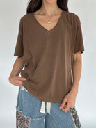 Person wearing a brown t-shirt and blue pants against a white background