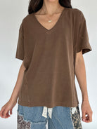 Person wearing a brown V-neck t-shirt with a plain background
