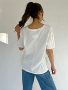 Person wearing a white shirt and blue jeans against a plain background