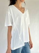 Person wearing a white t-shirt and blue jeans against a plain background