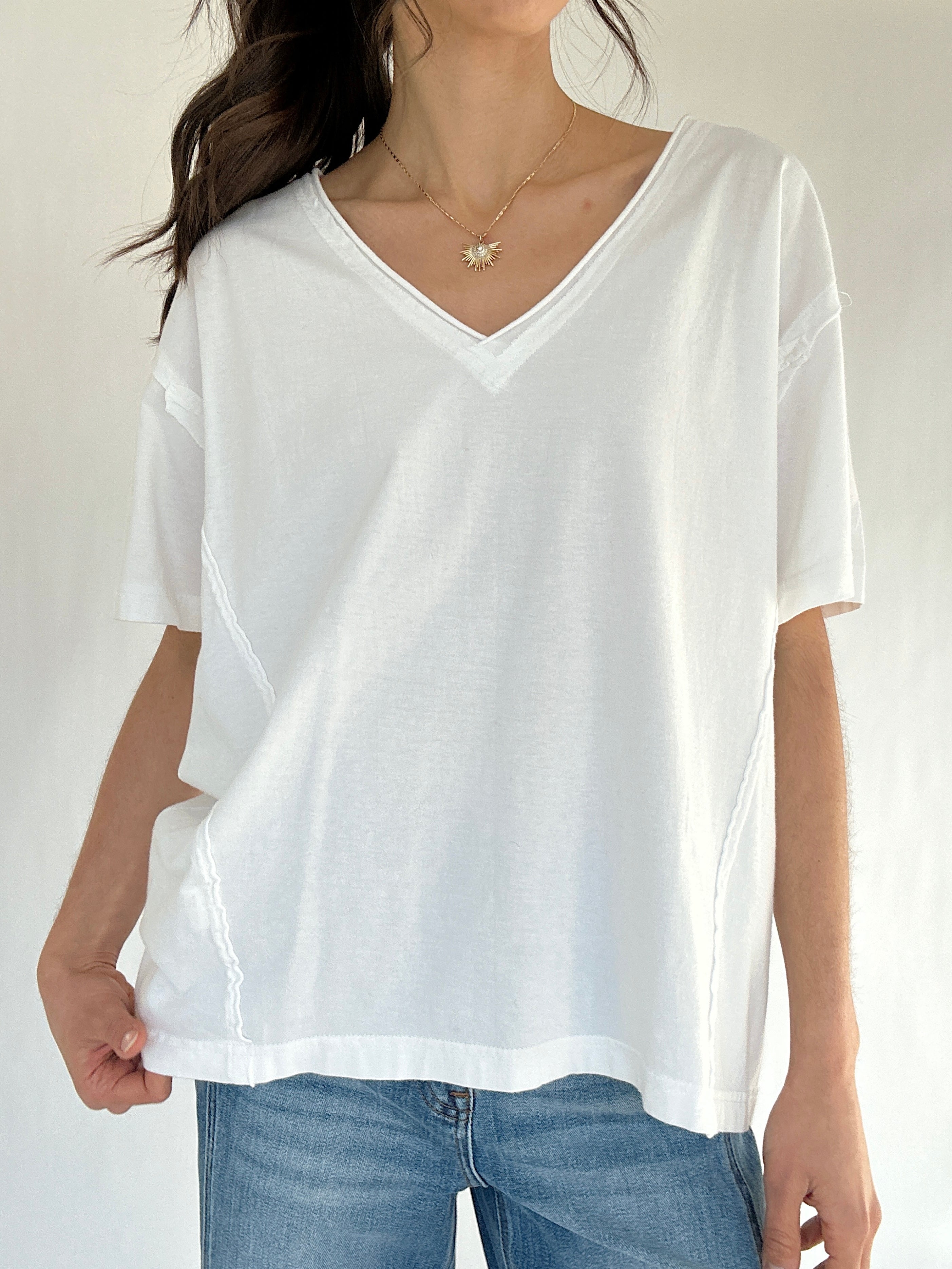 Person wearing a white oversized t-shirt and blue jeans on a plain background