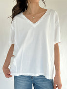 Person wearing a white oversized t-shirt and blue jeans on a plain background