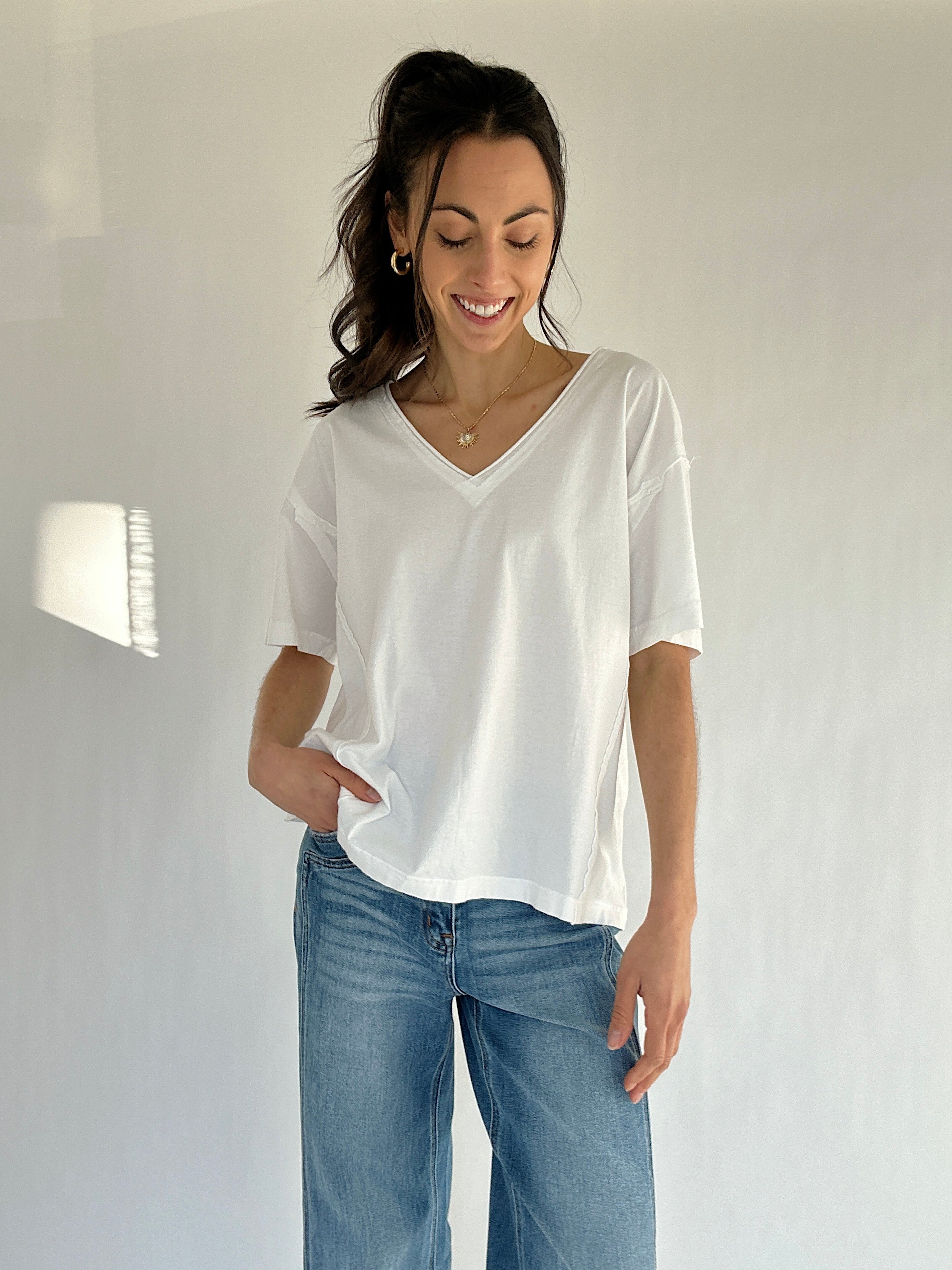 Woman wearing a white t-shirt and blue jeans against a plain background