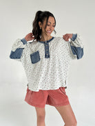 Woman wearing a floral long sleeve top with blue accents and rust shorts on a white background