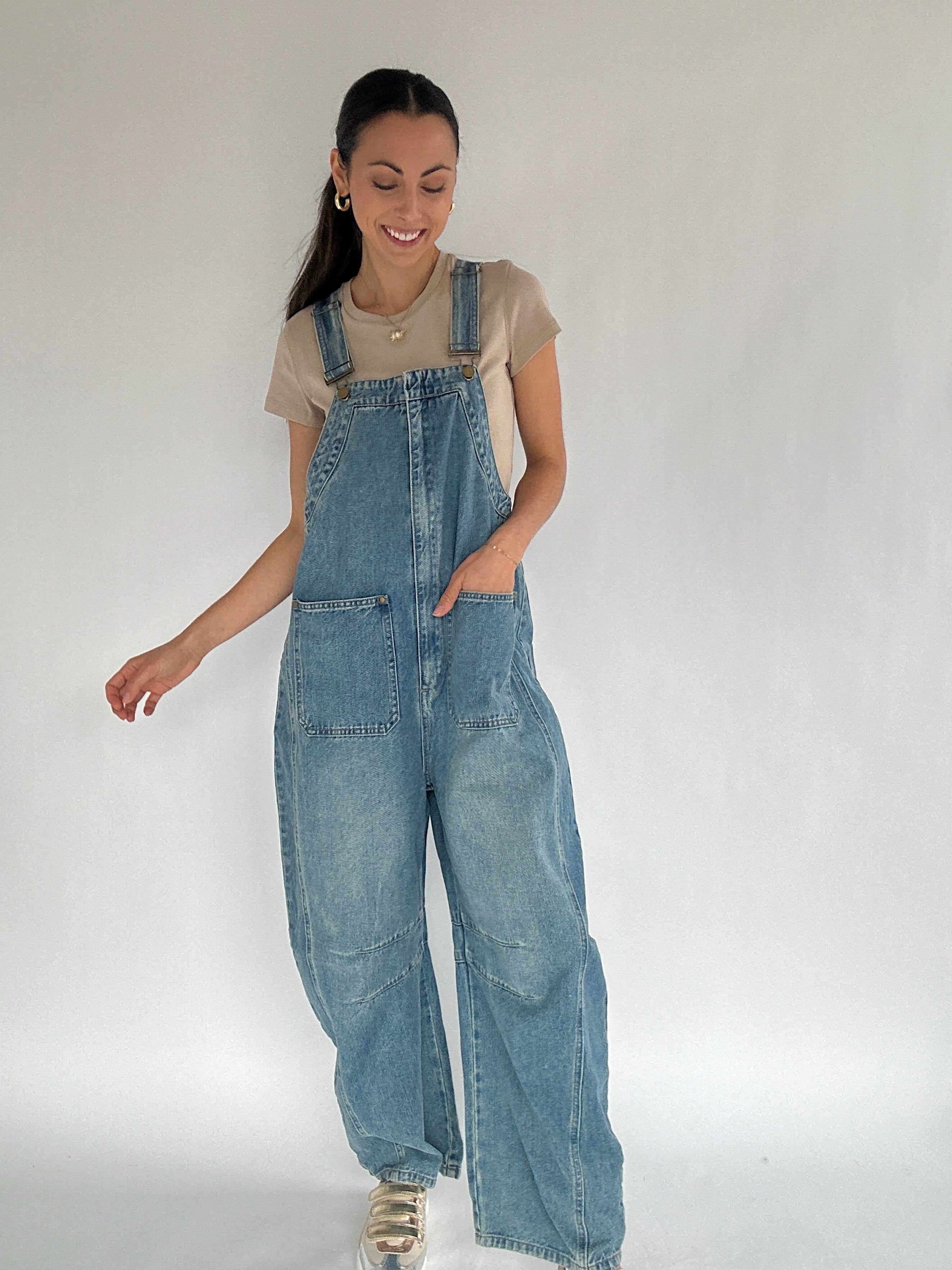 Woman wearing blue denim overalls on a plain background
