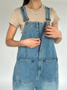 Person wearing a denim overalls with a plain background showing front zipper detail