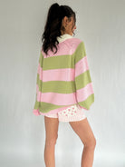Person wearing a pink and green striped sweater with a white background from back