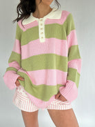Person wearing a green and pink striped sweater with a plain background