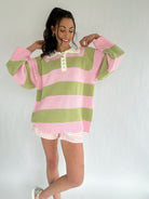 Woman wearing a pink and green striped sweater over a white shirt with a plain background