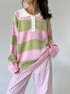 A person wearing a pink and light green striped knit sweater with a cream collar and button placket, paired with pink-and-white gingham pants, against a plain light gray wall.