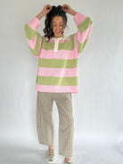 Person wearing a pink and green striped sweater with plaid pants on a white background