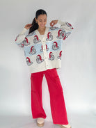 Woman wearing a light blue and white striped cardigan with santa faces on a white background