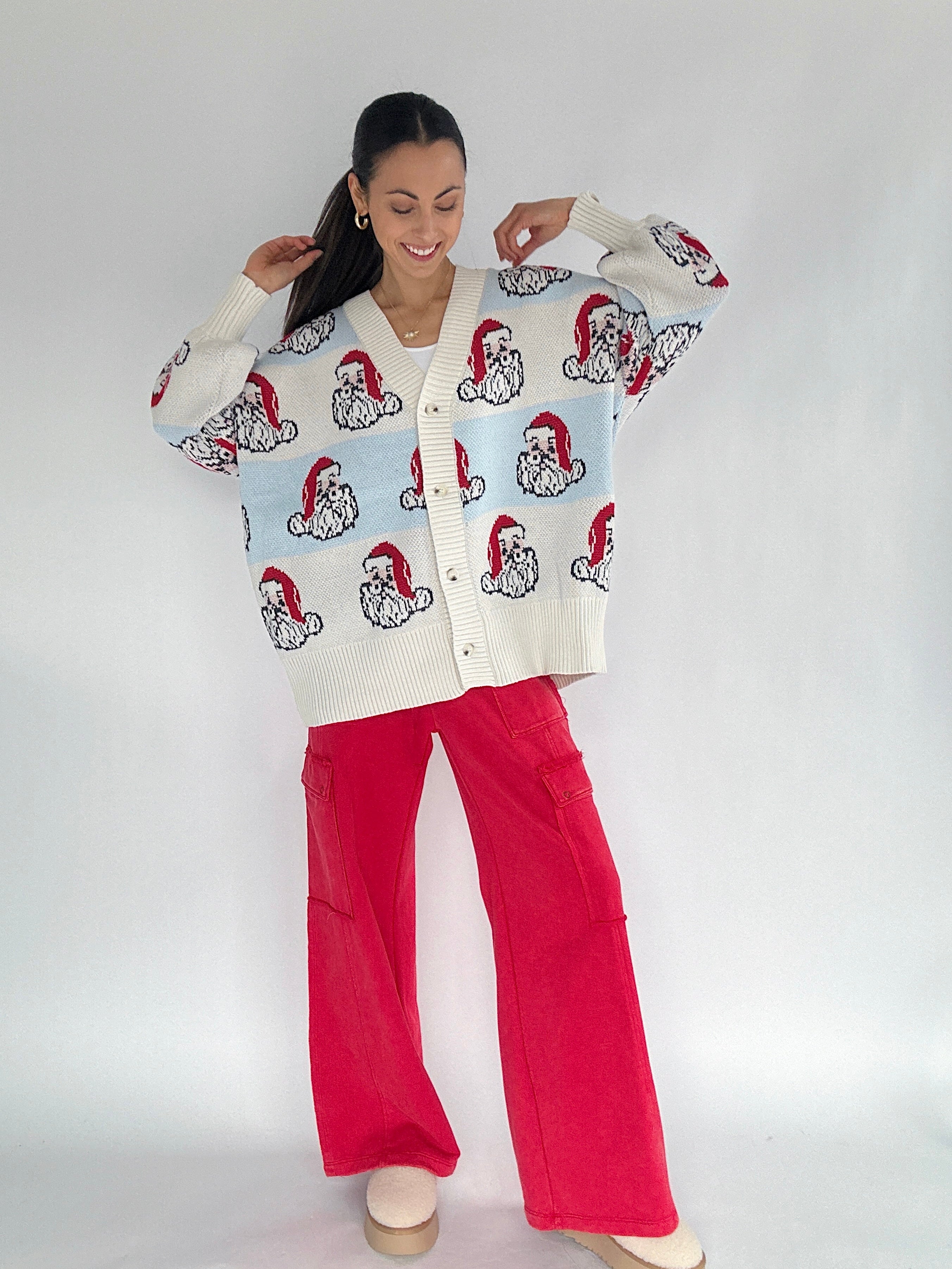 Woman wearing a light blue and white striped cardigan with santa faces on a white background
